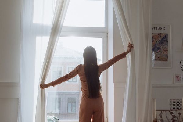 Calm person sitting near a window with soft morning light, suggesting a peaceful start.